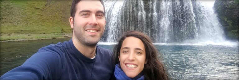 a couple in front of a lake and waterfall