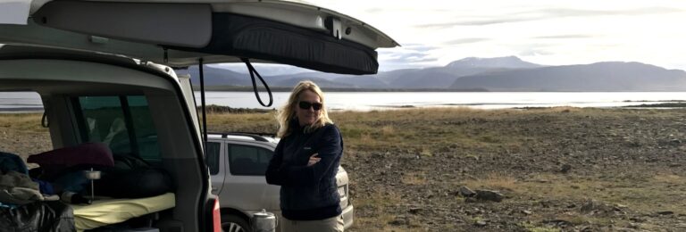 woman with sunglasses standing next to open rent.is camper