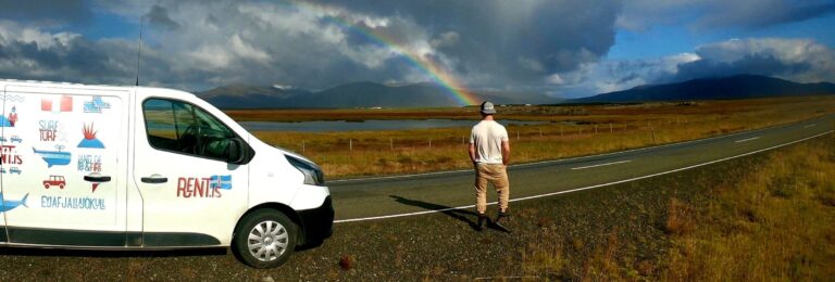 rent.is camper van, man standing looking at a lake and rainbow