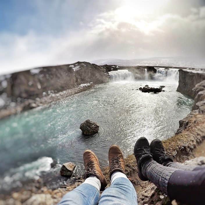 two pairs of feet next to a large lake