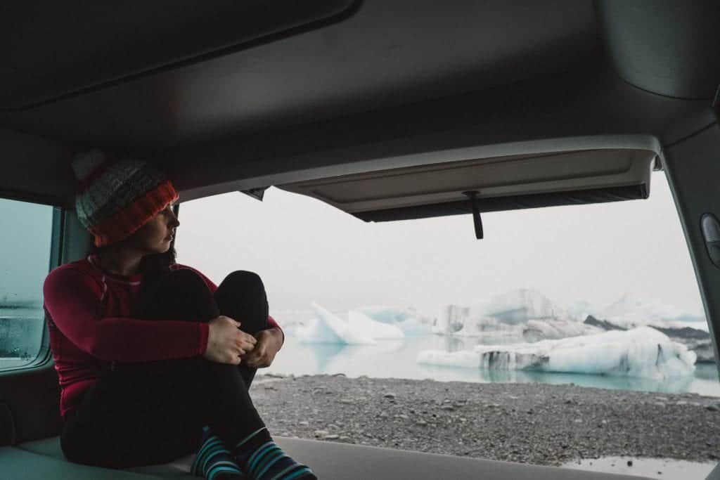 woman sitting inside VW california camper looking at glacier lagoon