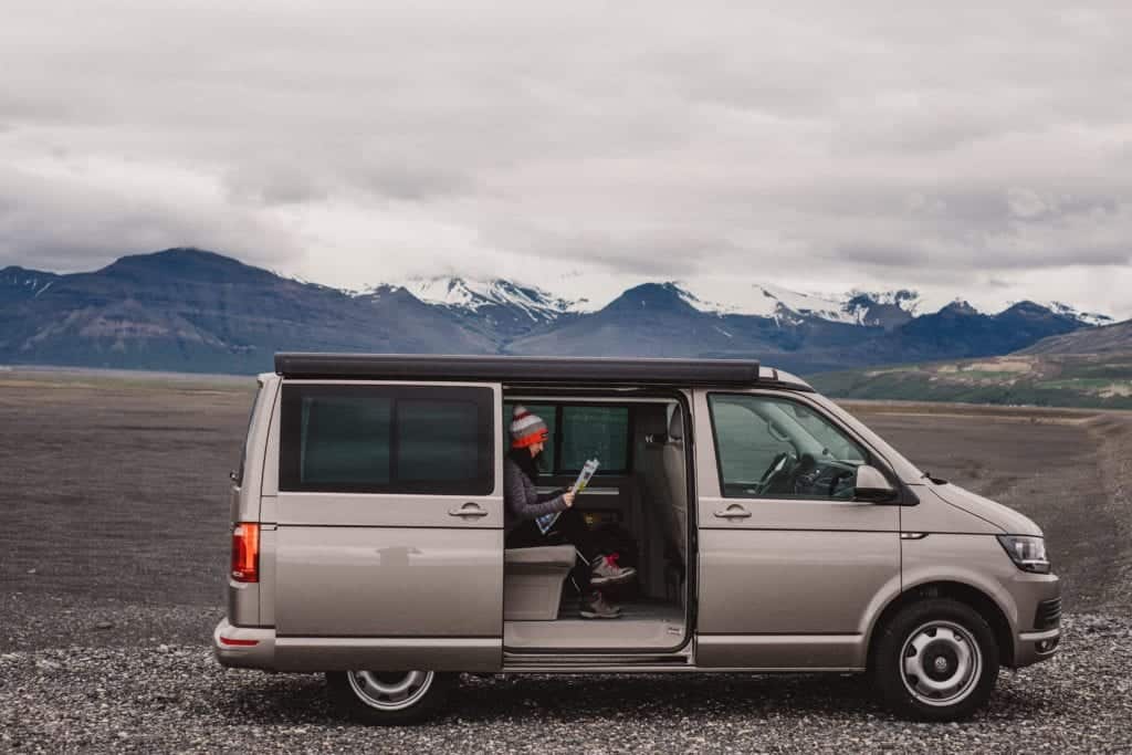 woman sitting inside a VW california camper van in nature