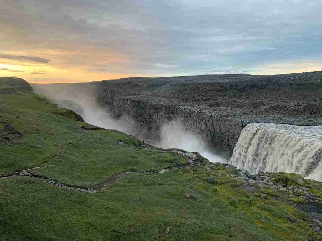 A beautiful waterfall by grass, whilst the sun is setting