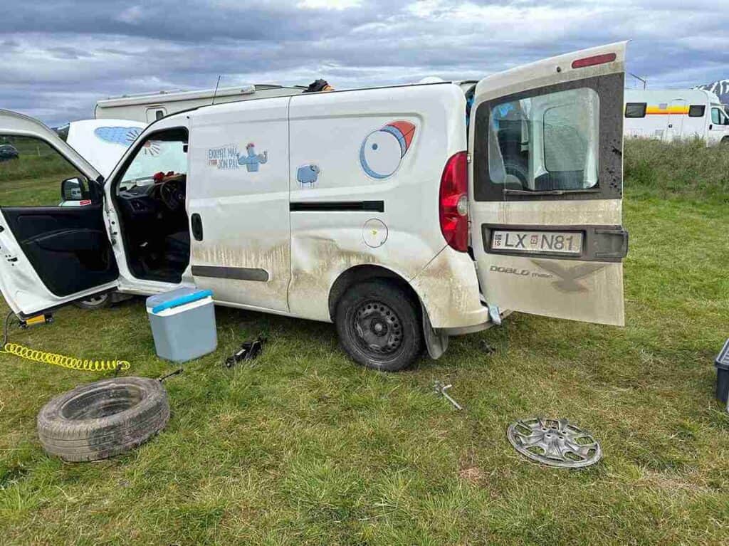 A fiat Doblo parked in a campsite with a newly changed spare tire.