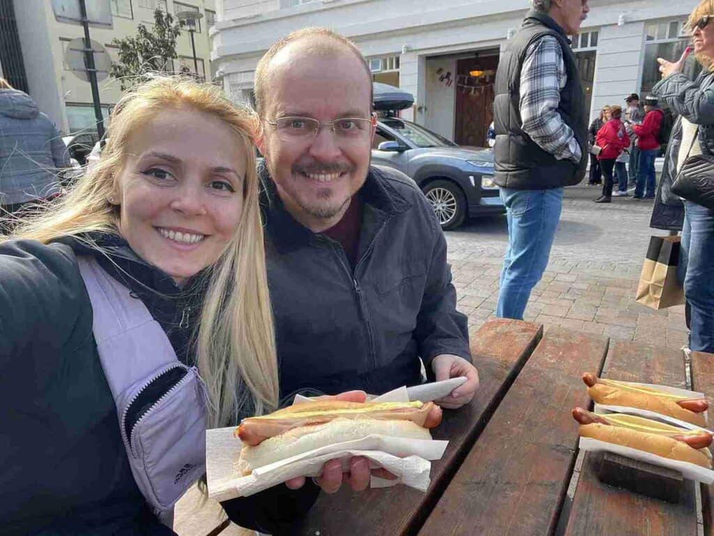 A couple sitting and eating hot dogs