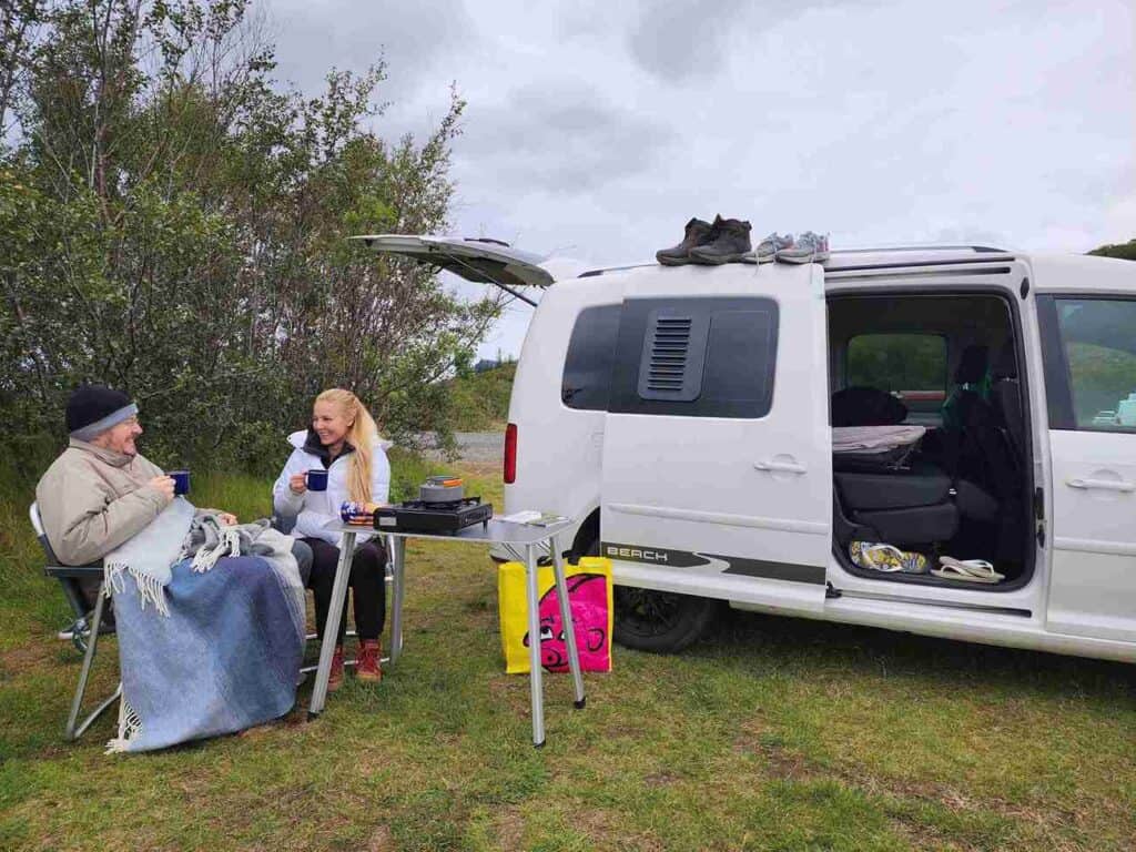 A couple sits and eats by the vw Caddy