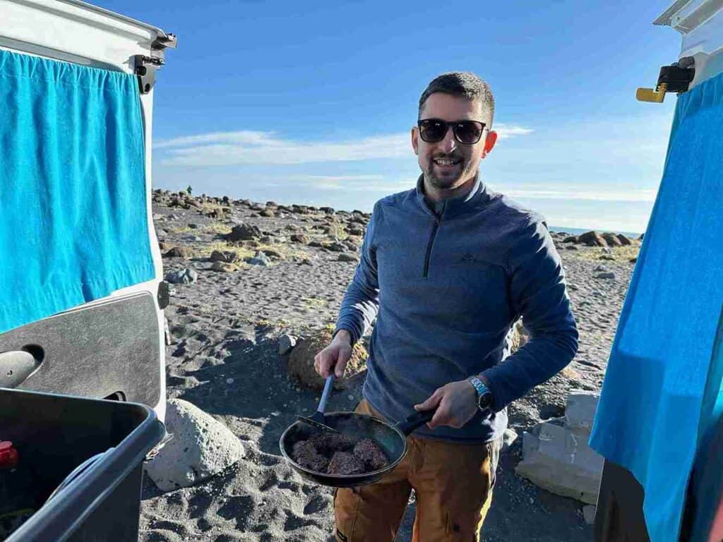 A man cooking at the beach in the Renault trafic