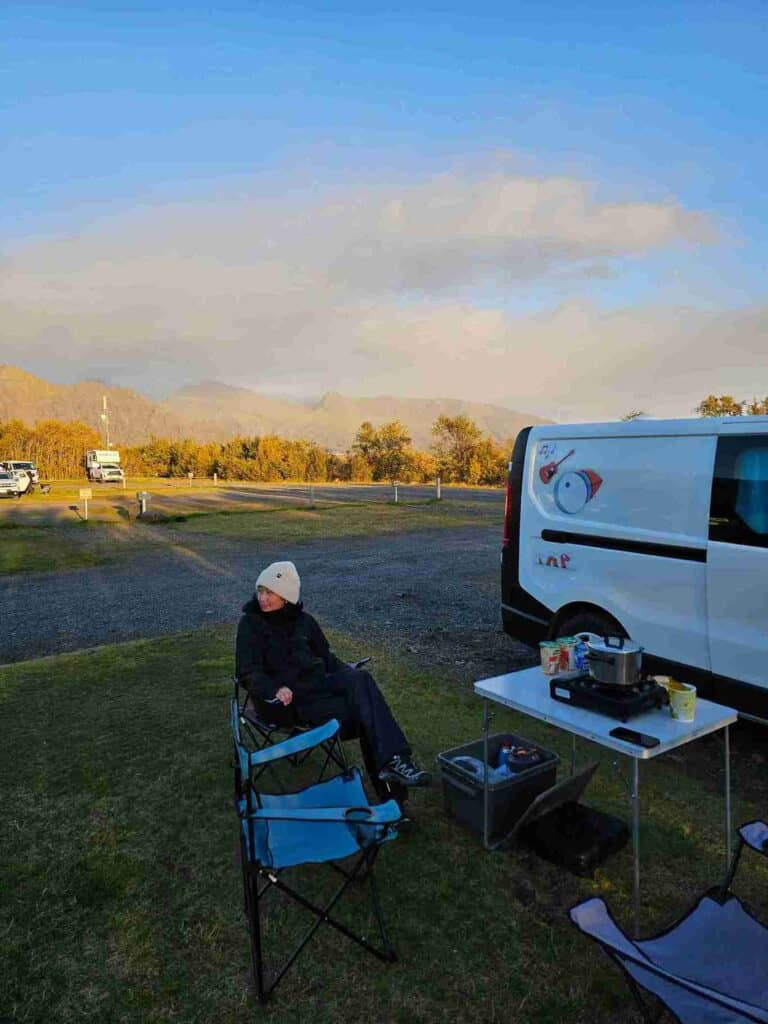 A woman wearing black sitting on a camping chair at a campsite
