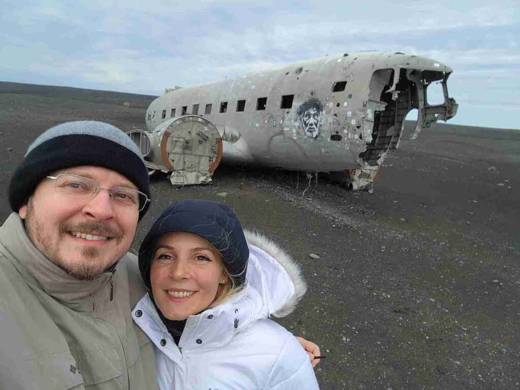 A couple standing by the Plane wreck of Sólheimasandur