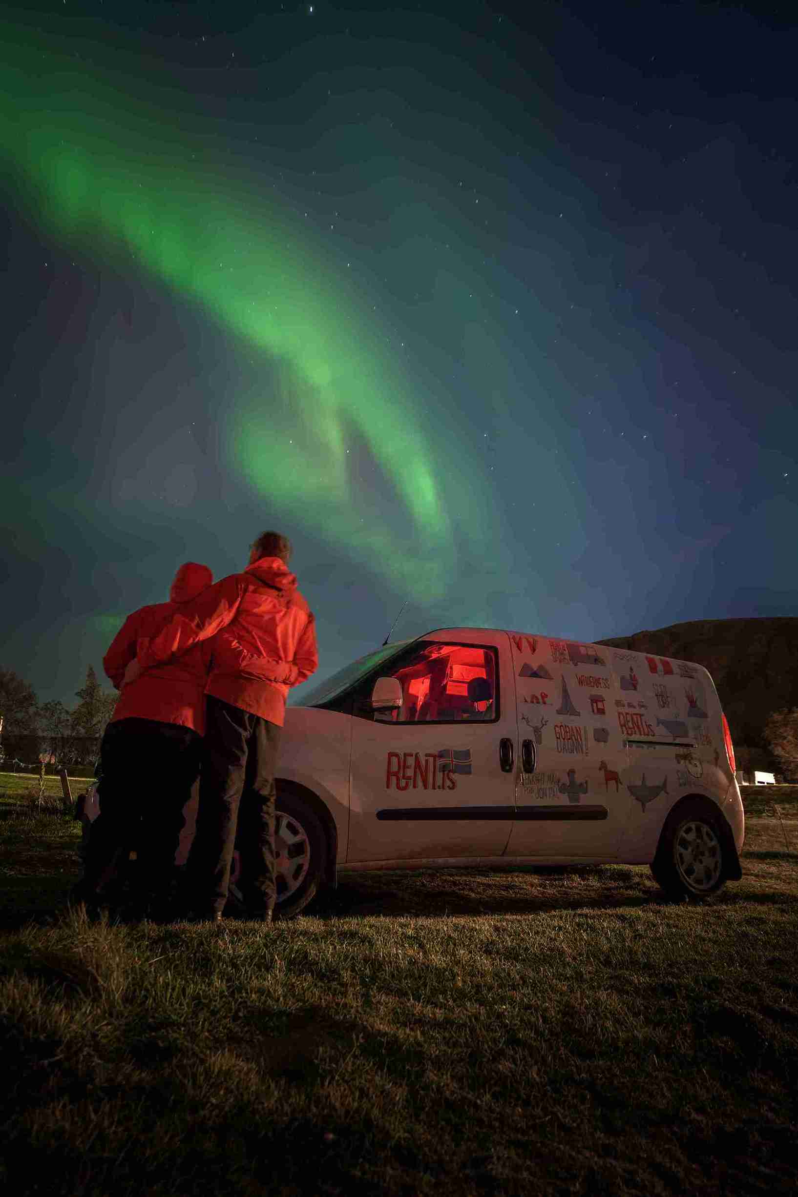 A couple and camper by northern lights