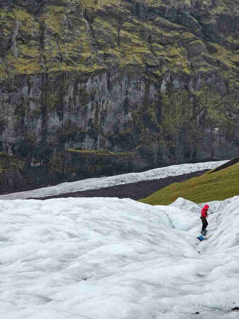 A person wearing red walking a glacier from afar