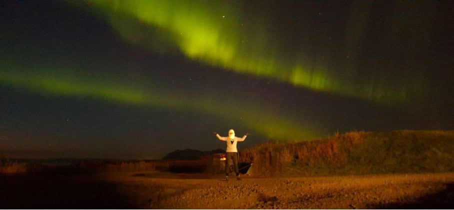 A person standing under Northern lights