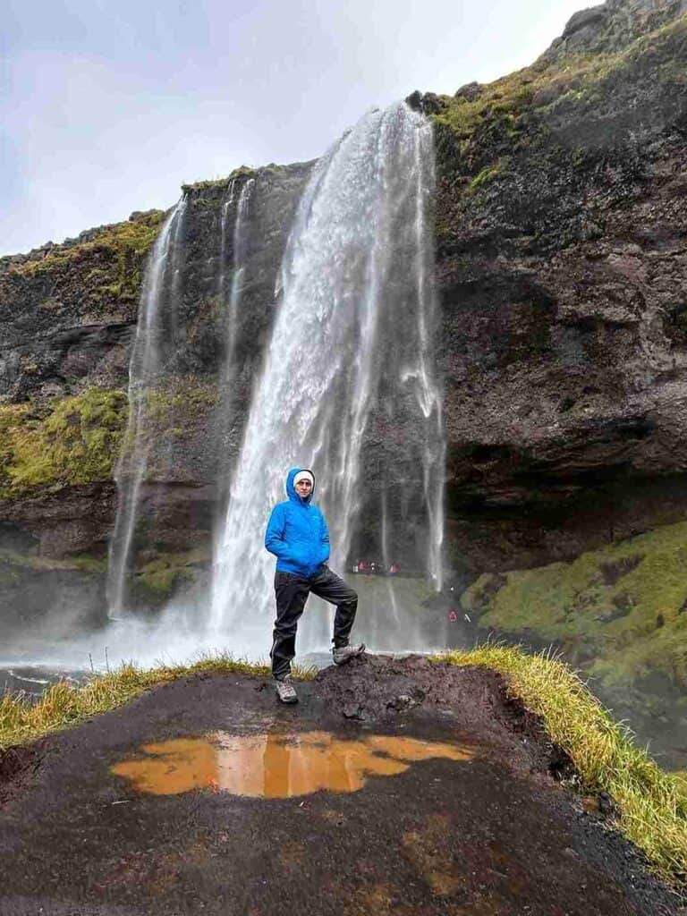 A woman standing on cliff posing by Seljarlandsfoss