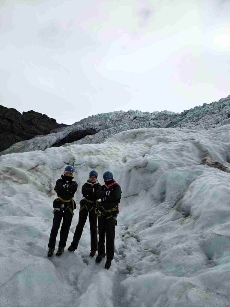 Three woman on a trip, standing on a glacier with safety gear